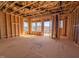A sunlit room with exposed framing features a doorway to a deck showcasing the open floor plan of the unfinished interior at 211 Pond View Ct # 5, Fuquay Varina, NC 27526