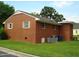 Rear view of a brick house on a grassy lot with trees, bins, and an A/C unit at 608 N Ellis Ave, Dunn, NC 28334