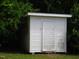A small white storage shed is nestled among green foliage at 608 N Ellis Ave, Dunn, NC 28334