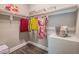 Bright walk-in closet with wood floor, white shelving, hanging clothes and storage baskets at 3177 Armeria Dr, Apex, NC 27502