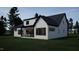 A modern white house with black trim sits on a lush green lawn, featuring a covered outdoor living space at 60 Chestnut Oak Dr, Youngsville, NC 27596