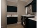 Modern laundry room with dark cabinetry, stainless steel washer/dryer, countertop, and hanging rod at 60 Chestnut Oak Dr, Youngsville, NC 27596
