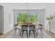 Bright dining room features a wood table, black chairs, modern lighting, and scenic backyard views at 6420 Tanner Oak Ln, Raleigh, NC 27613