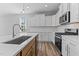 Modern kitchen boasts white cabinets, quartz countertops, stainless appliances, and wood-look floors at 709 Jamescroft Way, Rolesville, NC 27587