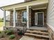 Inviting front porch with stone accents, black iron railings, and an elegant entryway at 8305 Cannon Grove Dr, Willow Springs, NC 27592