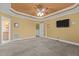 Bedroom featuring carpeted floors, a tray ceiling with fan, and a television mounted on the wall at 319 Fox Hollow Dr, Clayton, NC 27527