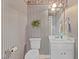 Powder room with striped wallpaper, white vanity, and a framed mirror at 319 Fox Hollow Dr, Clayton, NC 27527