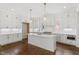 Bright kitchen featuring white cabinets, an island with sink, pendant lighting, and hardwood floors at 3302.5 Hall Pl, Raleigh, NC 27607