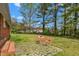 Backyard featuring a stone patio area with chairs, surrounded by mature trees offering shade and privacy at 2169 Northcrest Dr, Elon, NC 27244
