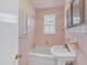 Small pink tiled bathroom with patterned wallpaper, shower, and pedestal sink at 229 Davis Mill Rd, Selma, NC 27576