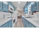 A galley kitchen with blue cabinets and white appliances leads into the dining area at 229 Davis Mill Rd, Selma, NC 27576