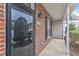 Brick front porch and entry featuring storm door and address numbers at 9009 Grassington Way, Raleigh, NC 27615