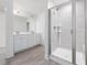 Bathroom with walk-in shower with tile surround, double sink vanity with white cabinetry and wood-look floors at 150 Whimbrel Ct, Lillington, NC 27546