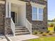Inviting front porch with stone accents, white railings and a dark front door at 150 Whimbrel Ct, Lillington, NC 27546