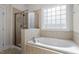 Bathroom with soaking tub, tiled shower, and glass block window for natural light and privacy at 4324 Brighton Ridge Dr, Apex, NC 27539