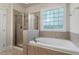 Bright bathroom featuring a glass shower and a soaking tub under a window at 4324 Brighton Ridge Dr, Apex, NC 27539