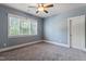 This bedroom features plush carpet, a ceiling fan and a bright window with a treed exterior view at 4324 Brighton Ridge Dr, Apex, NC 27539