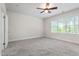 This sunny bedroom features plush carpet, a ceiling fan and a bright window with a treed exterior view at 4324 Brighton Ridge Dr, Apex, NC 27539