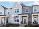 Charming townhouse featuring a covered porch, American flag, and two-tone gray siding at 728 Silo Park Dr, Wake Forest, NC 27587
