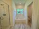Bathroom featuring a glass enclosed shower, soaking tub and a window overlooking a green yard at 19 Covey Rise Way, Lillington, NC 27546