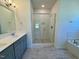 Bathroom featuring double sink vanity, glass shower and soaking tub with tile surround at 19 Covey Rise Way, Lillington, NC 27546