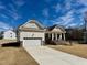 Charming exterior elevation with a stone skirt, two-car garage, and welcoming front porch at 19 Covey Rise Way, Lillington, NC 27546