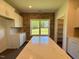 Kitchen features white cabinets, stainless appliances, brick accent wall, a white countertop island and view of backyard at 19 Covey Rise Way, Lillington, NC 27546