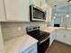 Modern kitchen features stainless appliances, a stylish backsplash, quartz countertop, and white cabinets at 19 Covey Rise Way, Lillington, NC 27546