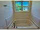 Bright bathroom with a soaking tub and a window with a view of the neighboring house at 19 Covey Rise Way, Lillington, NC 27546