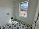 Laundry room with patterned tile floor, shelving, and a window with backyard view at 222 Grand Griffon Way, Lillington, NC 27546