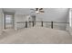 Bright bonus room featuring neutral carpet, a ceiling fan, and a staircase with white railings at 316 Spruce Pine Trl, Knightdale, NC 27545