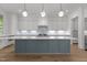 This kitchen features modern lighting, white cabinets and backsplash, and a large island with quartz countertop at 339 1/2 Mulberry St, Raleigh, NC 27604