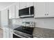 Close up of stainless steel microwave and stove top, granite countertops and subway tile backsplash at 40 Misty Mountain, Spring Hope, NC 27882