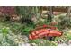 Picturesque backyard featuring a charming red wooden bridge over a koi pond, surrounded by lush plants and stone pathways at 5317 Burning Oak Ct, Raleigh, NC 27606