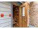 Exterior view of the sauna entrance, showcasing a wooden door, brick facade, and red emergency switch at 5317 Burning Oak Ct, Raleigh, NC 27606