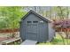 Charming gray shed with double doors, adjacent to lush greenery, enhancing the property's outdoor space at 5317 Burning Oak Ct, Raleigh, NC 27606