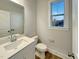 Bathroom features a white vanity, toilet, mirror, and a window offering natural light at 203 Pond Vw Ct # 1, Fuquay Varina, NC 27526