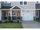 Charming townhome featuring stone accents, a one-car garage, and landscaped front yard at 207 Pond View Ct # 3, Fuquay Varina, NC 27526