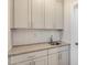 This is a well-lit wet bar featuring granite countertops, white cabinets, and a herringbone tile backsplash at 207 Pond View Ct # 3, Fuquay Varina, NC 27526