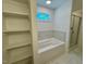 Bathroom featuring a soaking tub with tiled backsplash and shelving at 262 Grand Griffon Way, Lillington, NC 27546