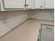 Close up of modern, light countertop with white cabinets and light-colored, horizontal stacked backsplash at 262 Grand Griffon Way, Lillington, NC 27546