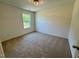This bedroom has neutral walls and carpeting with a window that provides a pleasant view at 45 Covey Rise Way, Lillington, NC 27546