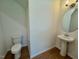 Well-lit powder room featuring a pedestal sink and round mirror, and light hardwood floors at 45 Covey Rise Way, Lillington, NC 27546
