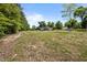 View of the backyard and gray home with large yard and mature trees surrounding the property at 670 Mcadams Rd, Hillsborough, NC 27278