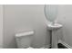 Bathroom featuring a white toilet, pedestal sink, and round mirror against a neutral wall at 107 Ethel Ln, Angier, NC 27501