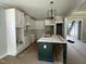 Bright kitchen with white cabinets, modern light fixtures, and large dark island at 136 Bar Code Ct, Wendell, NC 27591