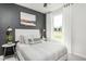 Bedroom with gray accent wall, a white upholstered bed and a window overlooking the lawn at 2308 Beeblossom Pl, Fuquay Varina, NC 27526