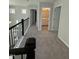 Upstairs hallway features grey carpet, black railing, and entryways into bedrooms and bathrooms at 2391 Englemann Dr Dr # 124, Apex, NC 27502