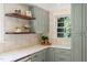 Bright kitchen features shaker cabinets, wood shelves, and white countertops under natural light from a window at 320 W Orange St, Hillsborough, NC 27278