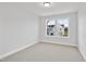 Well-lit bedroom showcasing neutral carpet, freshly painted walls, and a view of the neighborhood at 520 Eversden Dr, Zebulon, NC 27597